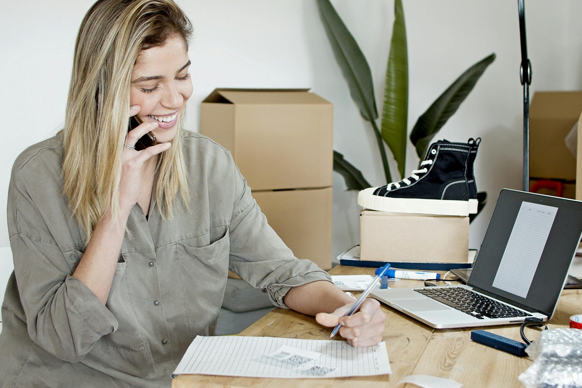 Woman on phone writing in notebook