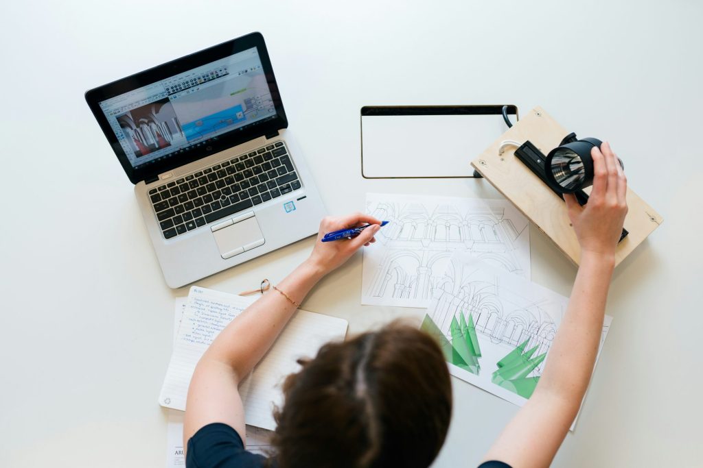 Woman writing and working on laptop